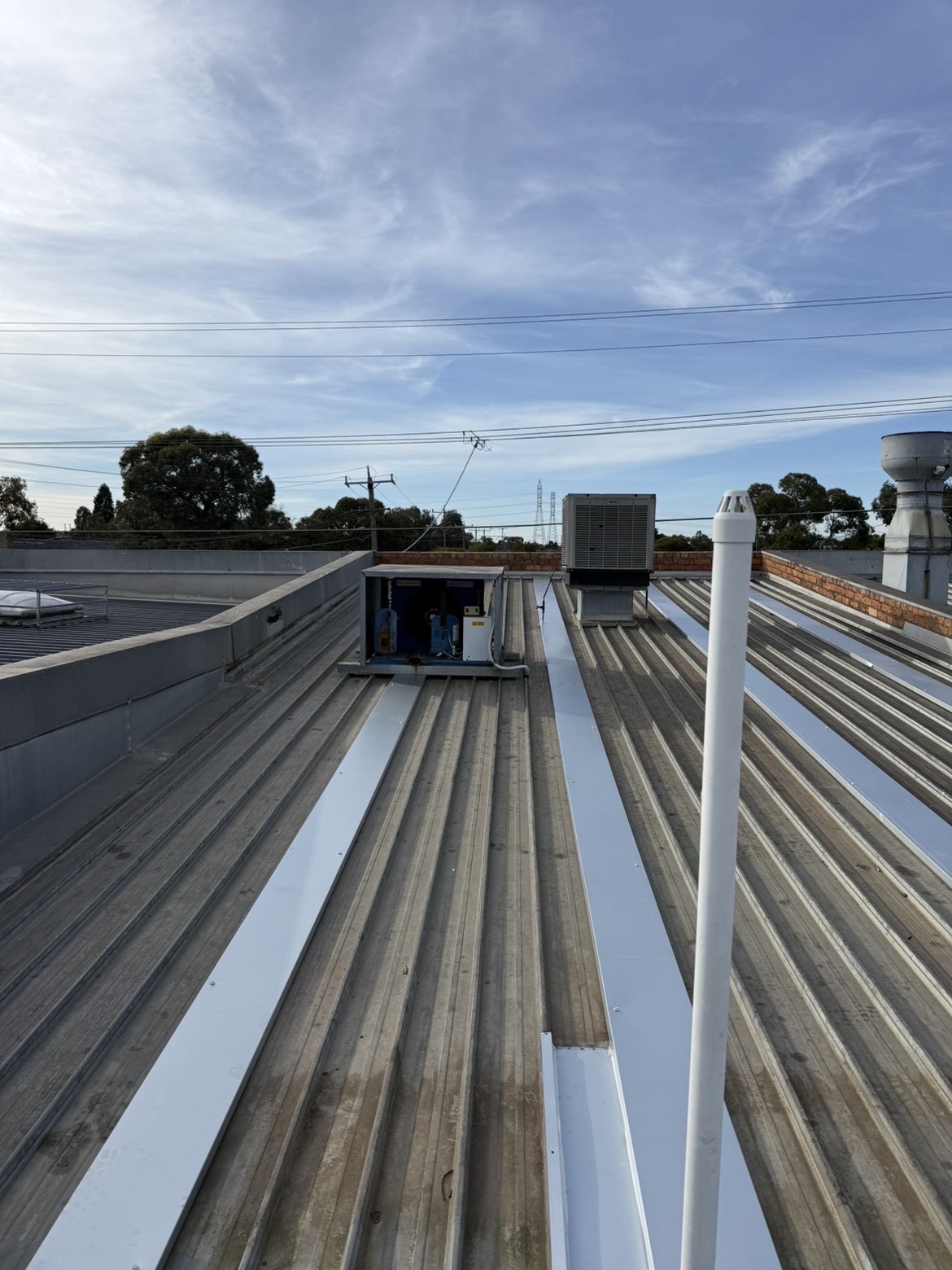 Metal flashing detail beside HVAC units on a commercial metal roof