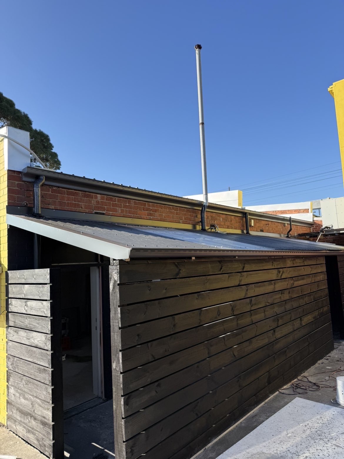 Dark metal roofing and new guttering installed on a timber structure