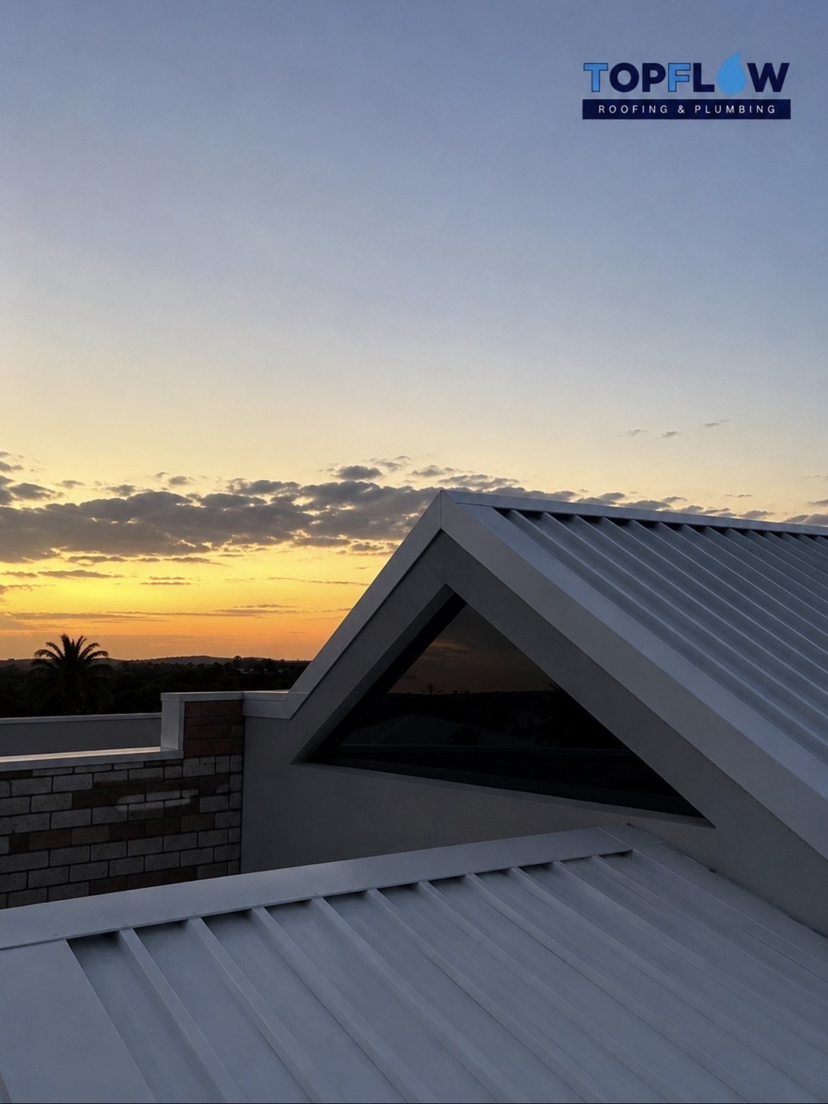 Finished metal roof peak against a sunset sky