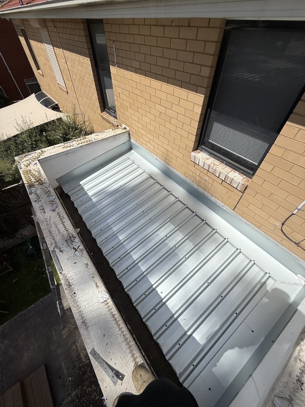 New metal roofing and flashing installed against a brick wall